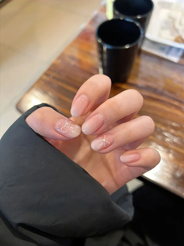 Móng tay ngắn màu hồng nude bóng với họa tiết trắng tinh tế