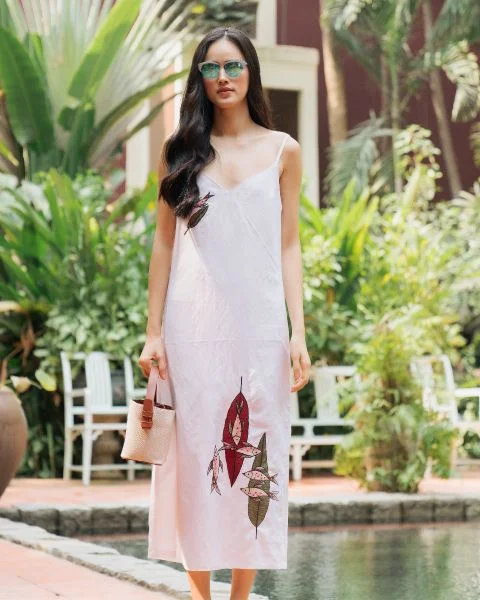 Người mẫu mặc những mẫu đầm linen đẹp có họa tiết thêu nghệ thuật ở sân vườn.